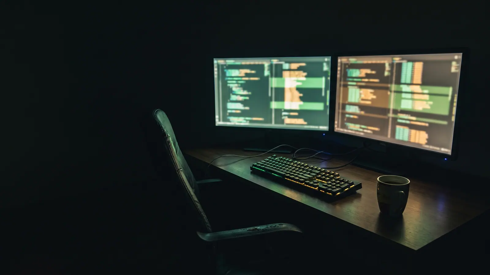 A developer's dark desk lit by a terminal's green monitor glow at night